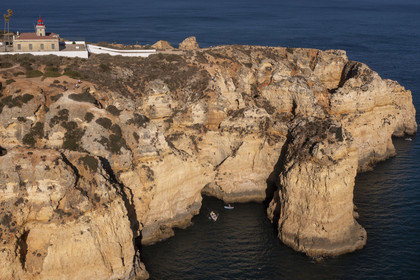 Portugal, Algarve, Lagos, phare à la pointe de Ponta da Piedade, découverte à pied, en bateau et en stand up paddle des grottes dans les falaises escarpées (vue aérienne)