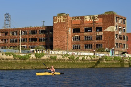 Spain, Basque Country, Biscay Province, Bilbao, kayaker going up the river Nervion towards the mouth, industrial wasteland of Deusto, former industrial building