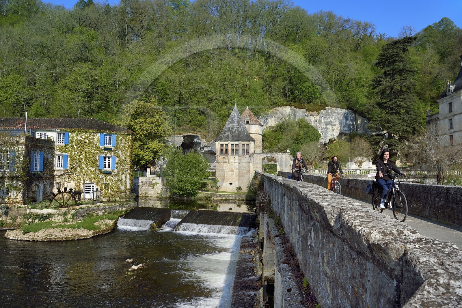 France, Dordogne (24), Brantôme, Pont Coudé sur la Dronne et le Moulin de L'Abbaye à gauche, ancien moulin du XVIe siècle transformé en Hotel****-Restaurant de charme, le pavillon Renaissance et la tour qui formaient la porte fortifiée en arrière plan, cyclistes sur la véloroute la Flow Vélo