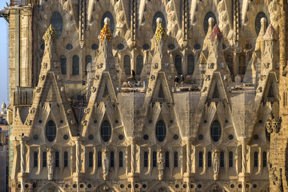 Spain, Catalonia, Barcelona, Eixample district, Sagrada Familia basilica by Catalan modernist architect Antoni Gaudi, listed as a UNESCO World Heritage Site, peaks topped with mosaics in the shape of fruits surrounding the construction site on the roof of the nave here on the Passion facade side