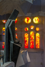 Spain, Catalonia, Barcelona, Eixample district, Sagrada Familia basilica by Catalan modernist architect Antoni Gaudi, listed as a UNESCO World Heritage Site, bronze statue of Saint George (Sant Jordi) by the sculptor Subirachs in the center of the interior of the Glory facade and the facade side of the Passion of the Nave with its warm-colored stained glass windows