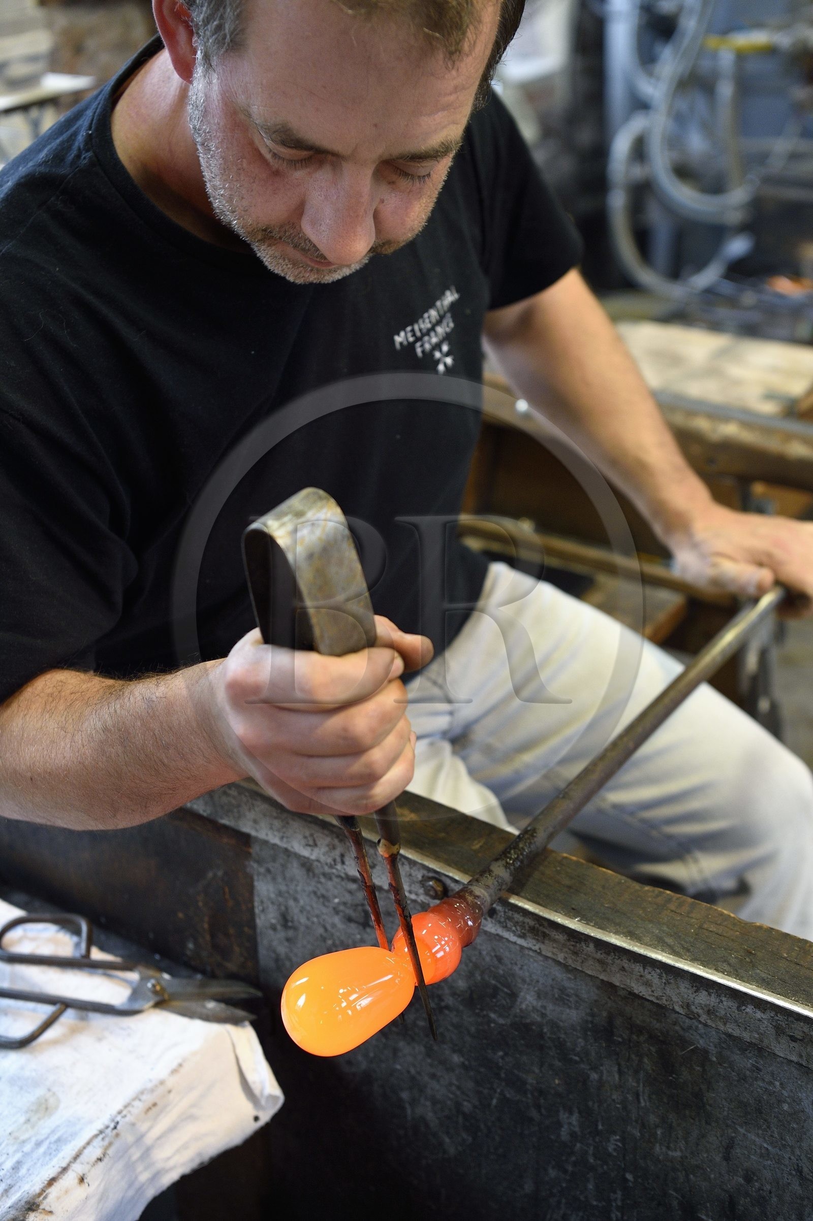 France, Moselle (57), Meisenthal, Centre international d’Art verrier (CIAV), l'atelier de soufflage, fabrication artisanale d'une boule de Noël, le souffleur et maitre verrier Jean-Marc Schilt régularise la masse au marbre tout en effectuant une rotation continue de sa canne et préparation de la paraison avant le passage au moule