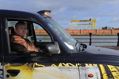 United Kingdom, Northern Ireland, Belfast, Billy Scott in his Black Cab in front of the Samson and Goliath gantry cranes from Harland and Wolff that have become city landmarks