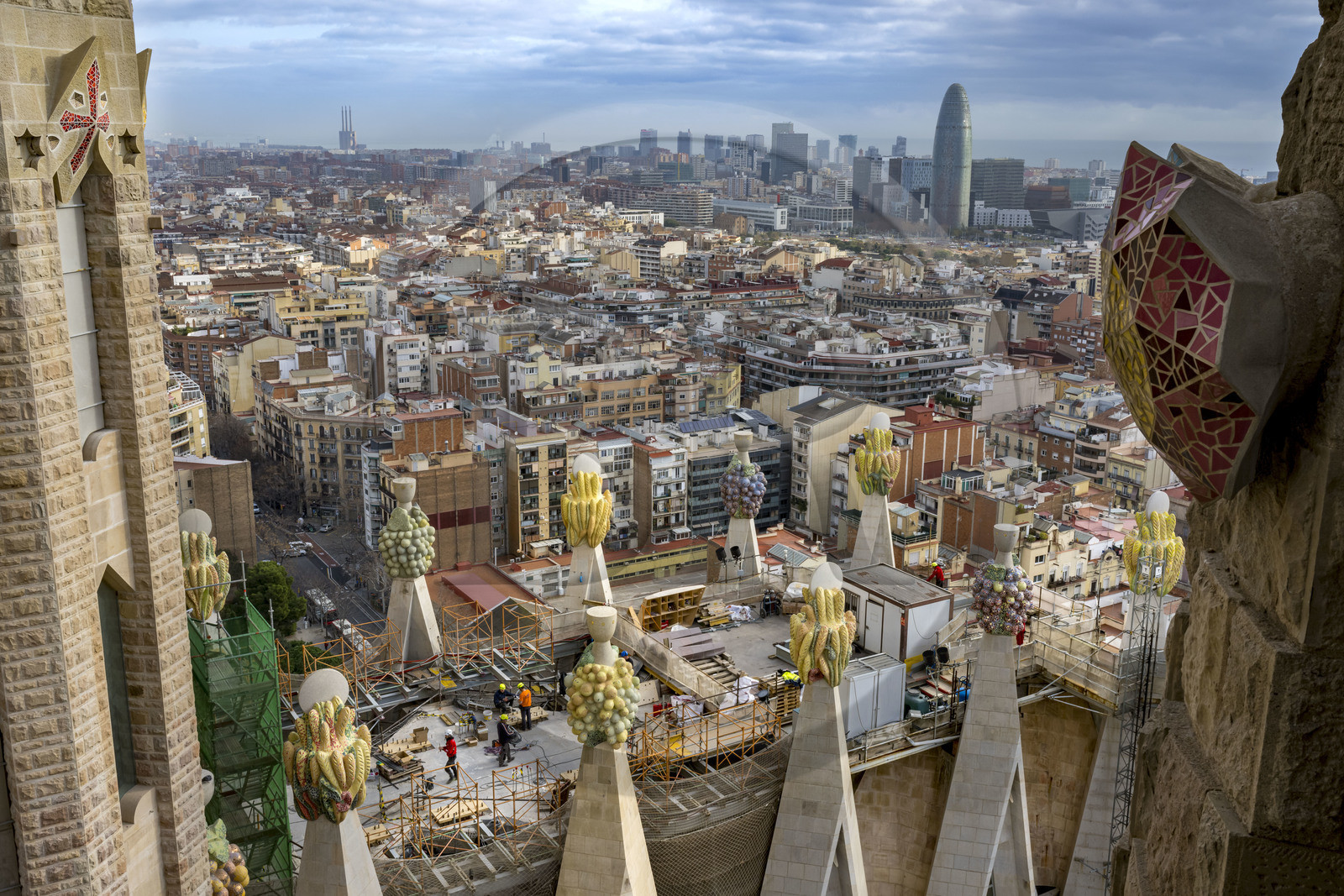 Espagne, Catalogne, Barcelone, quartier de l'Eixample, basilique de la Sagrada Familia de l'architecte du modernisme catalan Antoni Gaudi classée Patrimoine Mondial de l'UNESCO, sommets surmontés de mosaïques en forme de fruits entourant le chantier sur le toit de la nef à l'arrière de la future facade de la Gloire, la Torre Agbar de l'architecte Jean Nouvel en arrière plan