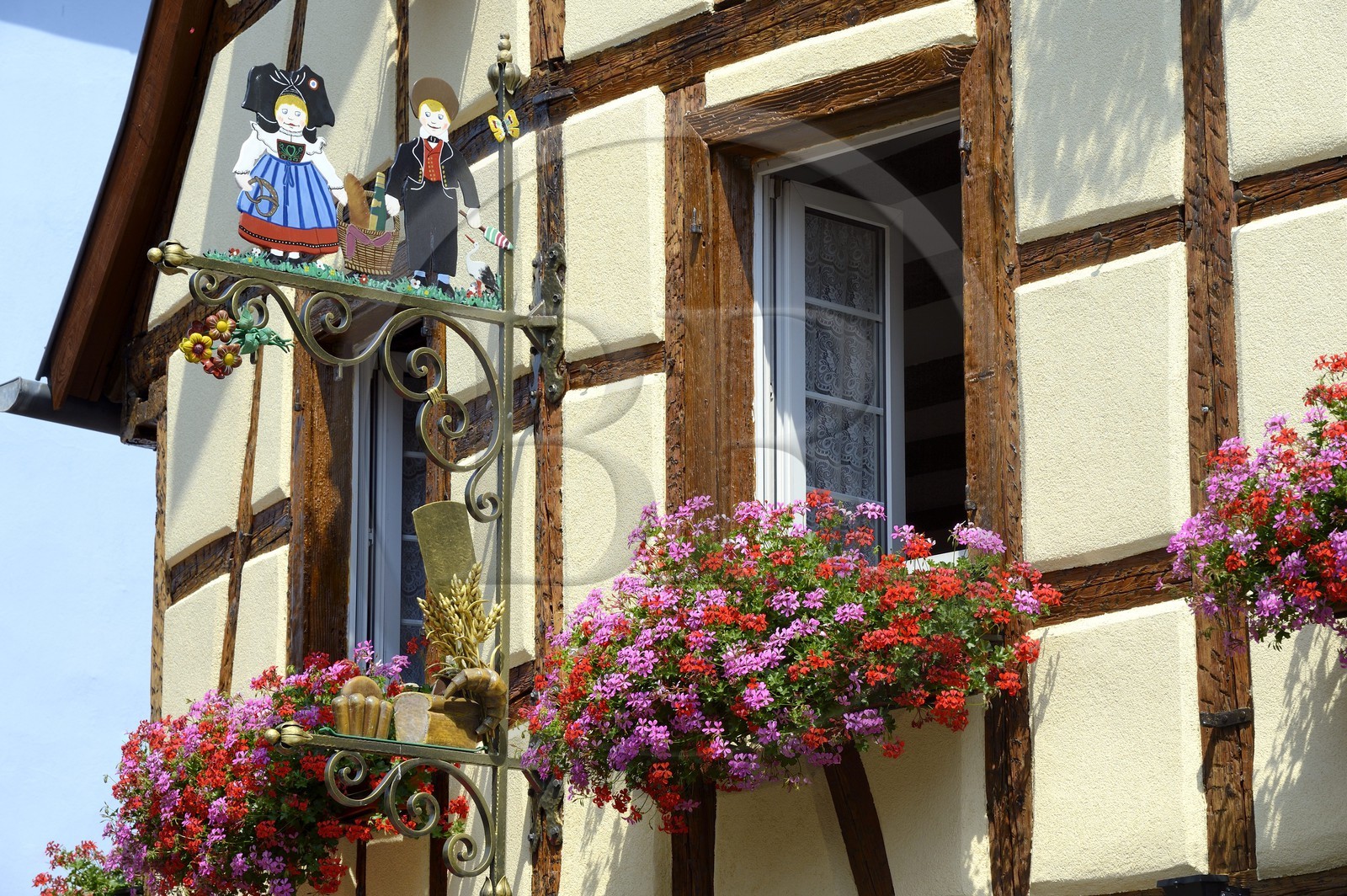 France, Haut-Rhin (68), Eguisheim, labellisé Les Plus Beaux Villages de France, enseigne de boulangerie avec des personnages en costume alsacien devant une maison à colombage