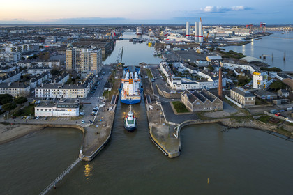 France, Loire-Atlantique (44), Saint-Nazaire, le General Cargo Rotra Mare transporte des sections des mats d'éoliennes et entre dans le bassin à flot du port (en arrière plan) par  l'écluse sud, qui est aussi le lieu de l’Opération Chariot lancée en 1942 par les Britanniques (vue aérienne)