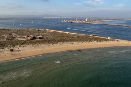Portugal, Algarve, Ria Formosa Natural Park, Faro, Island of Barreta or Deserta (Ilha da Barretta or Deserta), the lighthouse of Ilha do Farol part of  Ilha da Culatra in the background (aerial view)