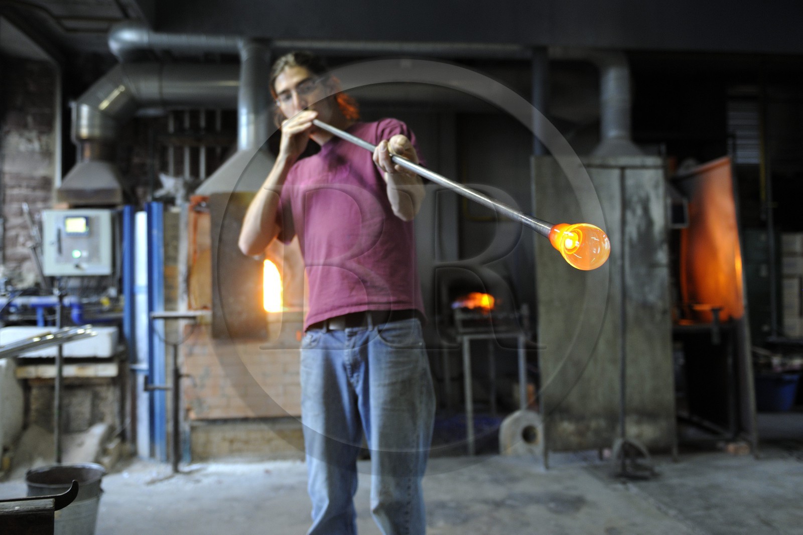 France, Moselle (57), Meisenthal, Thibaut souffleur au Centre international d’Art verrier (CIAV), fabrication d'une boule de Noël en verre. Tout en tournant la canne, il souffle dans la canne