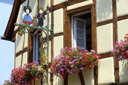 France, Haut Rhin, Eguisheim, labelled Les Plus Beaux Villages de France (The Most Beautiful Villages of France), baker sign with characters in typical outfit from Alsace in front of a half-timbered house