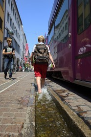 Germany, Baden-Wurttemberg, Freiburg im Breisgau, Back from school in the Kaiser-Joseph Strasse, one of the Bächle which are small open channel lining the sidewalks of the old town