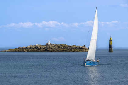 France, Finistère, Roscoff, islets exposed at low tide, sailboat passing off a daymark
