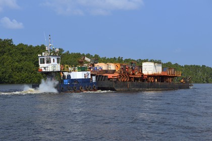 Gabon, province de Ogooué- Maritime, région de Port-Gentil, bateau poussant une barge d'engins de terrassement sur une rivière débouchant sur la baie du Cap Lopez, le manque de routes est compensé par l'utilisation des rivières