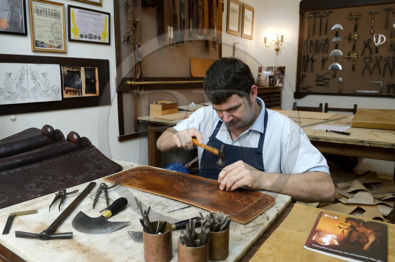 Argentine, province de Buenos Aires, San Antonio de Areco, atelier du maroquinier Martin Alvarez qui martèle le cuir d'un élément d'une selle Argentine, province de Buenos Aires, San Antonio de Areco, atelier du maroquinier Martin Alvarez qui martèle le cuir d'un élément d'une selle