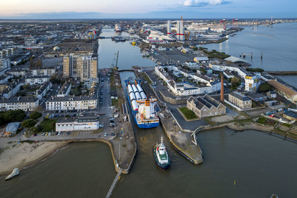France, Loire-Atlantique (44), Saint-Nazaire, le General Cargo Rotra Mare transporte des sections des mats d'éoliennes et entre dans le bassin à flot du port (en arrière plan) par  l'écluse sud, qui est aussi le lieu de l’Opération Chariot lancée en 1942 par les Britanniques (vue aérienne)