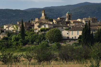 France, Vaucluse, Parc Naturel Regional du Luberon (Natural Regional Park of Luberon), Lourmarin, labelled Les Plus Beaux Villages de France (The Most Beautiful Villages of France), the clock tower and the  church bell tower, the massif of Luberon in background