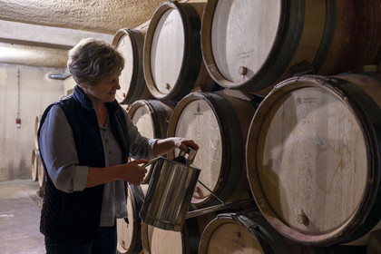 France, Cote d'Or, cultural Landscape of the climates of Burgundy listed as World Heritage by UNESCO, Route des Grands Crus (road of Vintage Wines), vineyard of the Côte de Nuits, Morey Saint Denis, Domaine Amiot et fils, Chantale Amiot uses a water bottle to top up the barrels to the bung