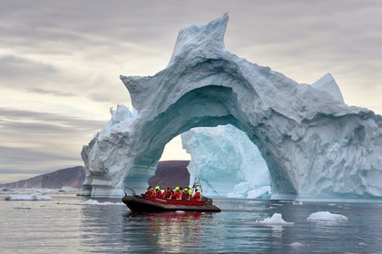 Greenland, North West coast, Baffin Sea, Inglefield Fjord towards Qaanaaq, iceberg forming an arch and an exploration PolarCirkel boat (zodiac) of the MS Fram cruse ship from Hurtigruten