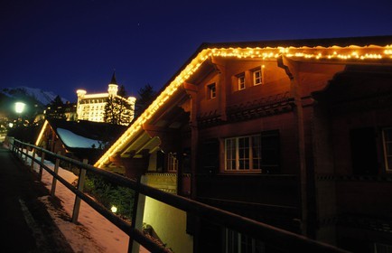 Switzerland, region of Bern (Bernese Oberland), Saanenland, Gstaad, the Palace Hotel by night behind a wooden chalet