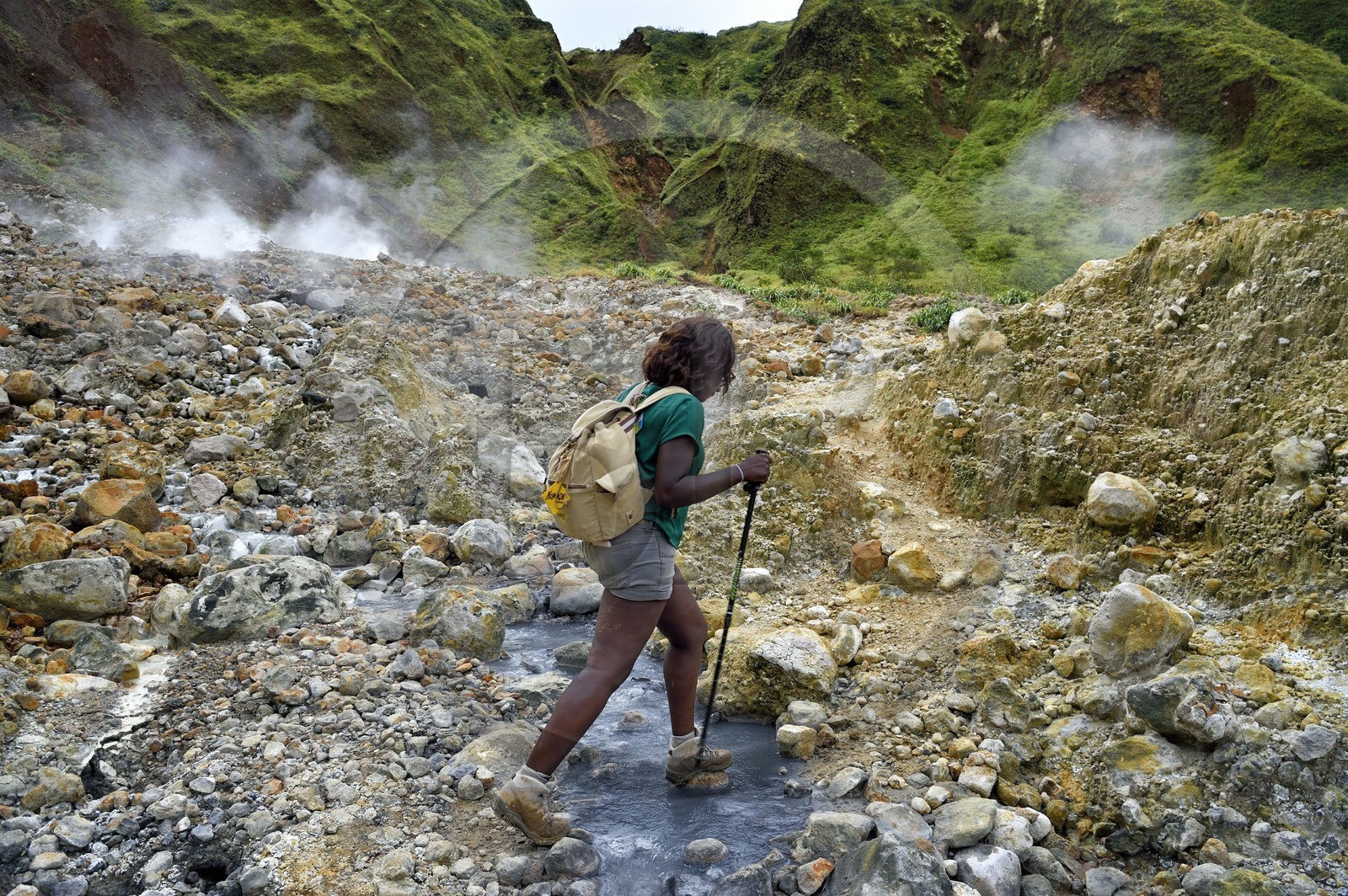 Caraïbes, Ile de la Dominique, Castle Bruce, Parc national du Morne Trois Pitons classé Patrimoine Mondial de l'UNESCO, la Vallée de la Désolation, randonneuse traversant une rivière aux sources d'eau chaude dont la couleur unique est due à la présence de calcium, de carbone, de soufre et de fer, sur le sentier menant au Boiling Lake