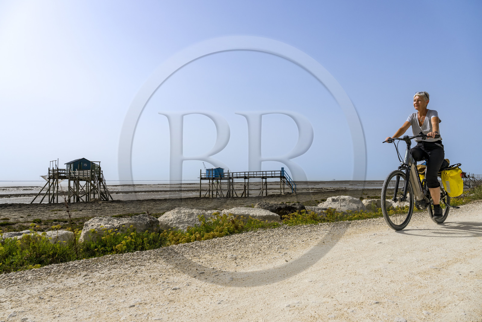 France, Charente-Maritime (17), Port-des-Barques, Ile Madame, cycliste en randonnée passant devant des cabanes sur pilotis appelées carrelets à marée basse