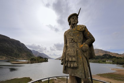 United Kingdom, Scotland, Highlands, statue of an Highlander on Glenfinnan Monument, to mark the spot where Bonnie Prince Charlie started the battle to regain the crown and Loch Shiel