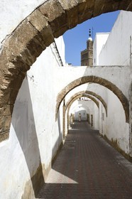 Maroc, Casablanca, la cité des Habous construite entre 1917 et 1955 par les architectes Auguste Cadet et Edmond Brion, rue avec arcades et la Mosquée Moulay Youssef en arrière plan