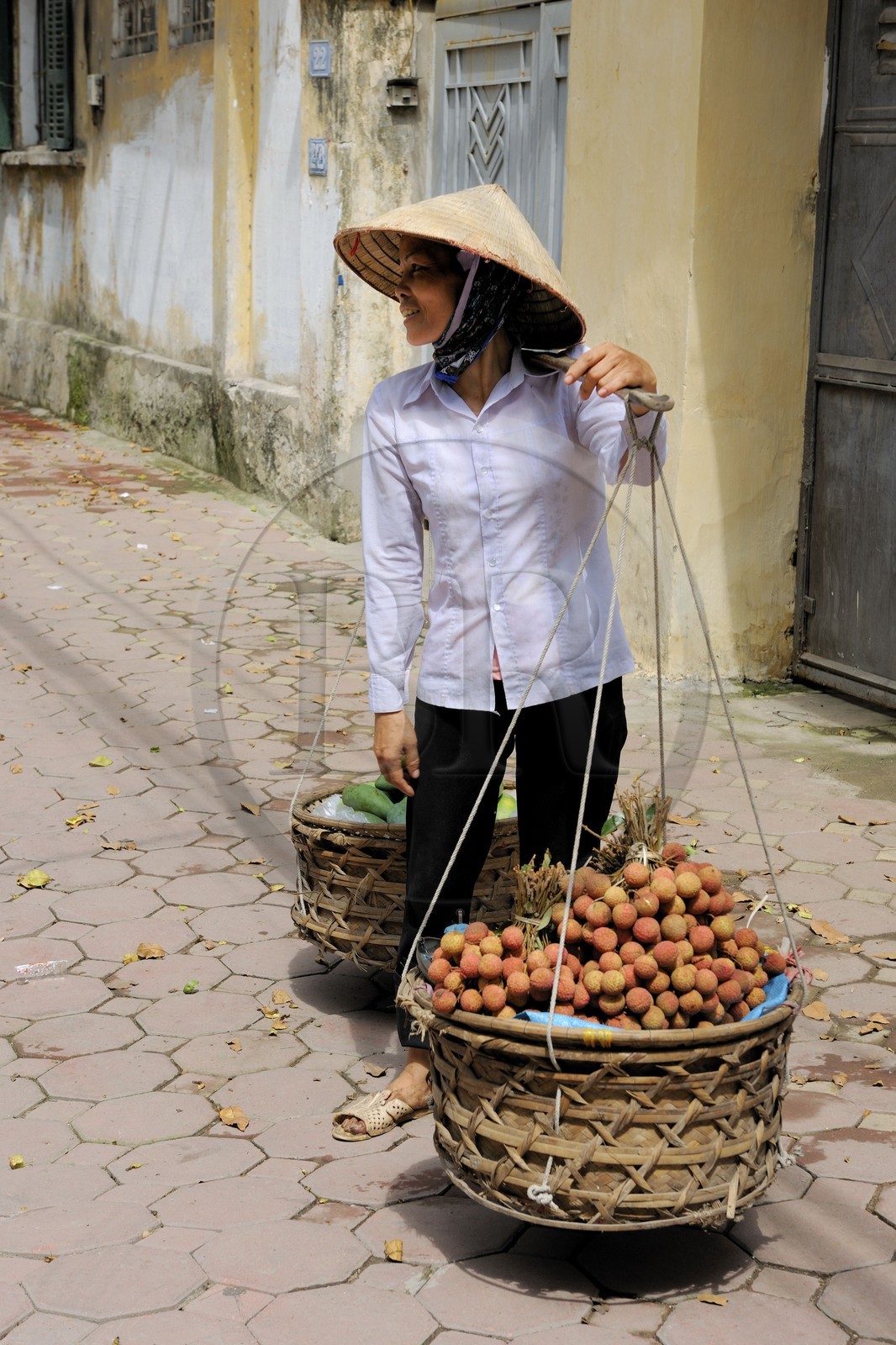 Vietnam, Hanoï, vieille ville, marchande de fruits (lychee) avec sa palanche
