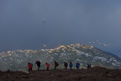 Italie, Sicile, iles Eoliennes, classées Patrimoine Mondial de l'UNESCO, ile de Stromboli, randonneurs dans l'ascension du volcan, le village de Stromboli et l'ilot de Strombolicchio en arrière plan