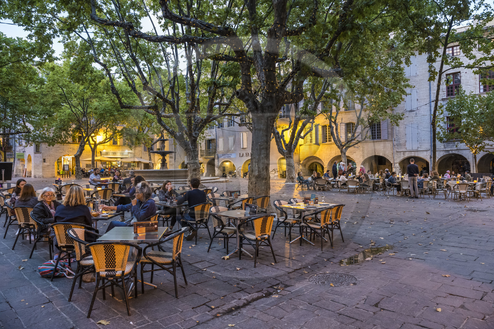 France, Gard (30), Uzès, la Place aux Herbes entourée de maisons à arcades et ses terrasses de café