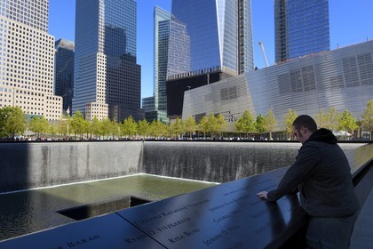 Etats-Unis, New York, Manhattan, 9 11 Memorial dessiné par l'architecte israélien Michael Arad qui consiste en une forêt d'arbres autour de deux étendues d'eau carrées avec deux grands trous en leur centre à l'endroit précis où se tenaient les deux tours et les noms gravés de victimes, le One World Trade Center (1WTC) en arrière plan