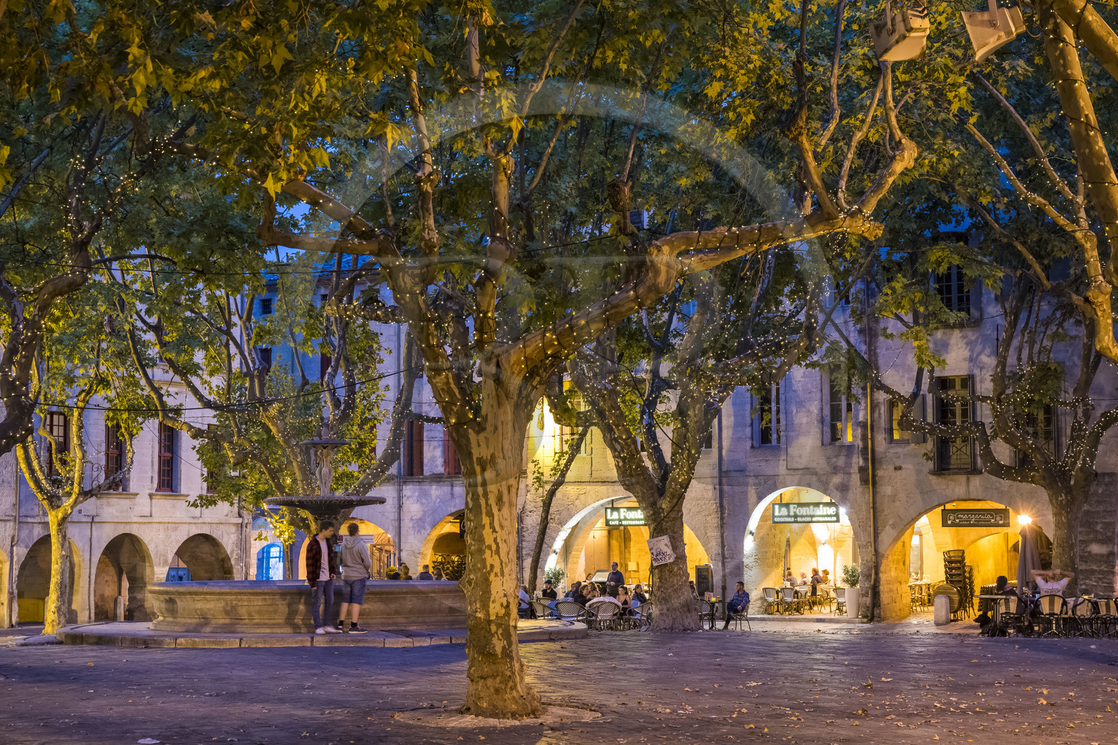 France, Gard (30), Uzès, la Place aux Herbes entourée de maisons à arcades et ses terrasses de café