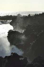 France, Ile de la Reunion, L'Etang Salé les Bains, la côte entre Le Gouffre et l'Etang du Gol, roches noires basaltiques d'origine volcanique tourmentées par l'océan, pêcheur à la ligne