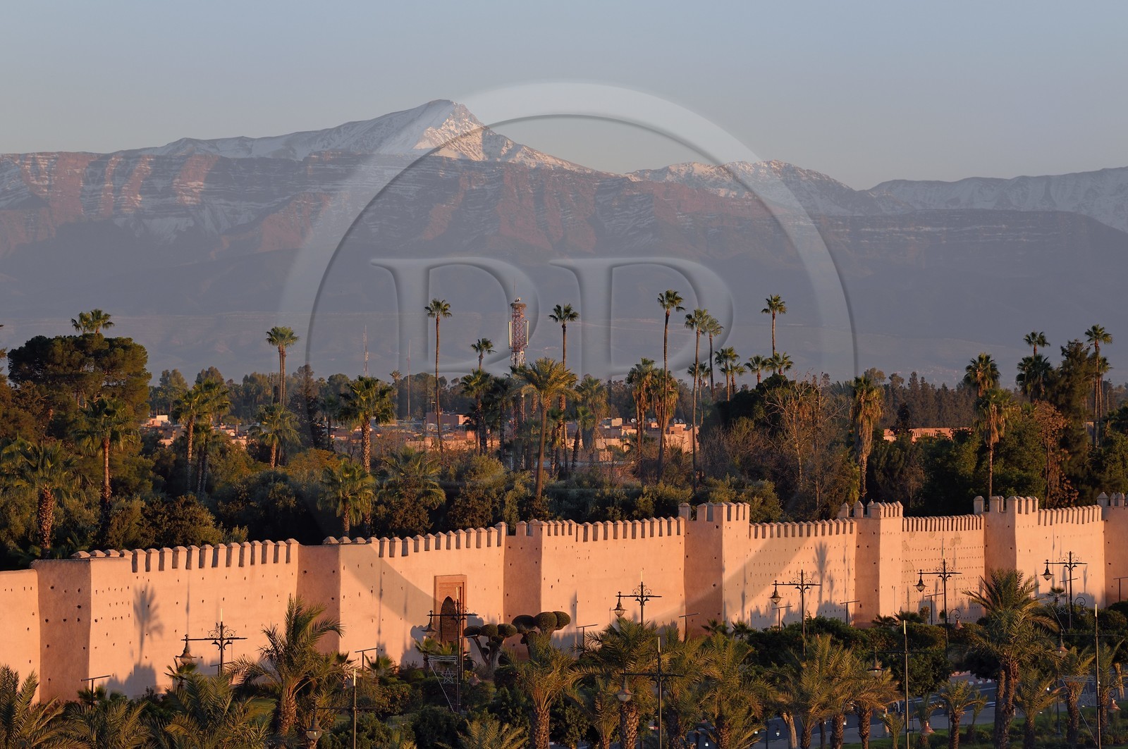 Maroc, Haut-Atlas, Marrakech, ville impériale, Médina classée Patrimoine Mondial de l'UNESCO, les remparts de la ville et le sommet de l'Oukaïmeden dans l'Atlas enneigé en arrière plan au soleil couchant