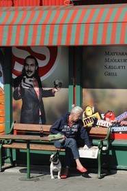 Iceland, Reykjavik, woman reading the newspaper in front of a grocery store