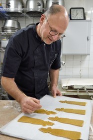 France, Meurthe-et-Moselle, Nancy, the pastry chef Didier Hulot making the gingerbread for Saint Nicholas Day, drawing on the already shaped dough