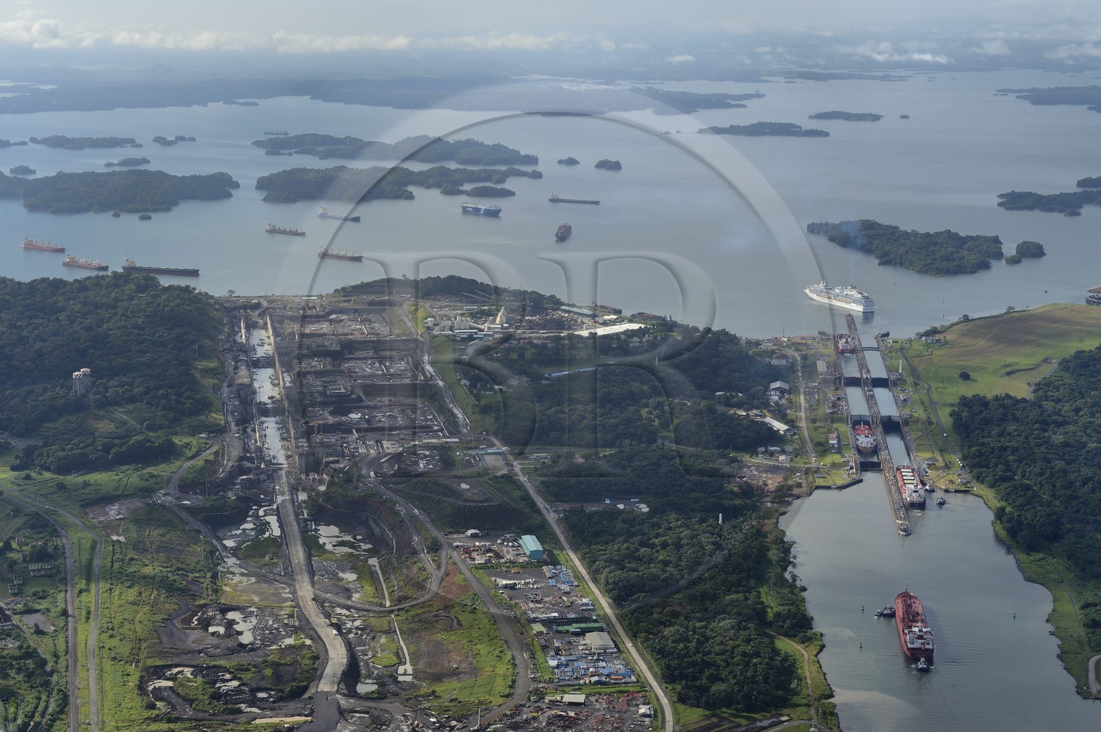 Panama, Colon province, Panama Canal, Panamax cargo passing the Gatun locks, the construction of the new locks on the left and the Gatun Lake in the background (aerial view)