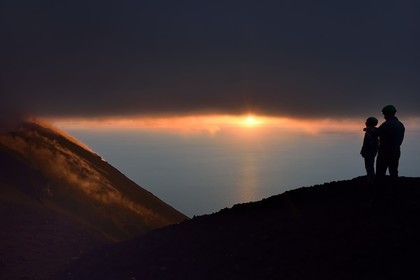 Italie, Sicile, iles Eoliennes, classées Patrimoine Mondial de l'UNESCO, ile de Stromboli, randonneurs observant les fumerolles d'une éruption sur les pentes du volcan actif au coucher de soleil