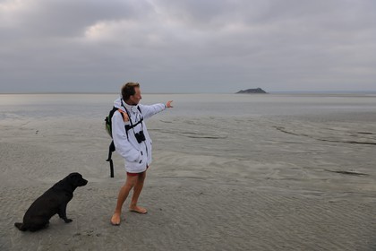 France, Manche (50), découverte de la Baie du Mont-Saint-Michel à pied avec le guide Romain Pilon qui pointe l'ile de Tombelaine