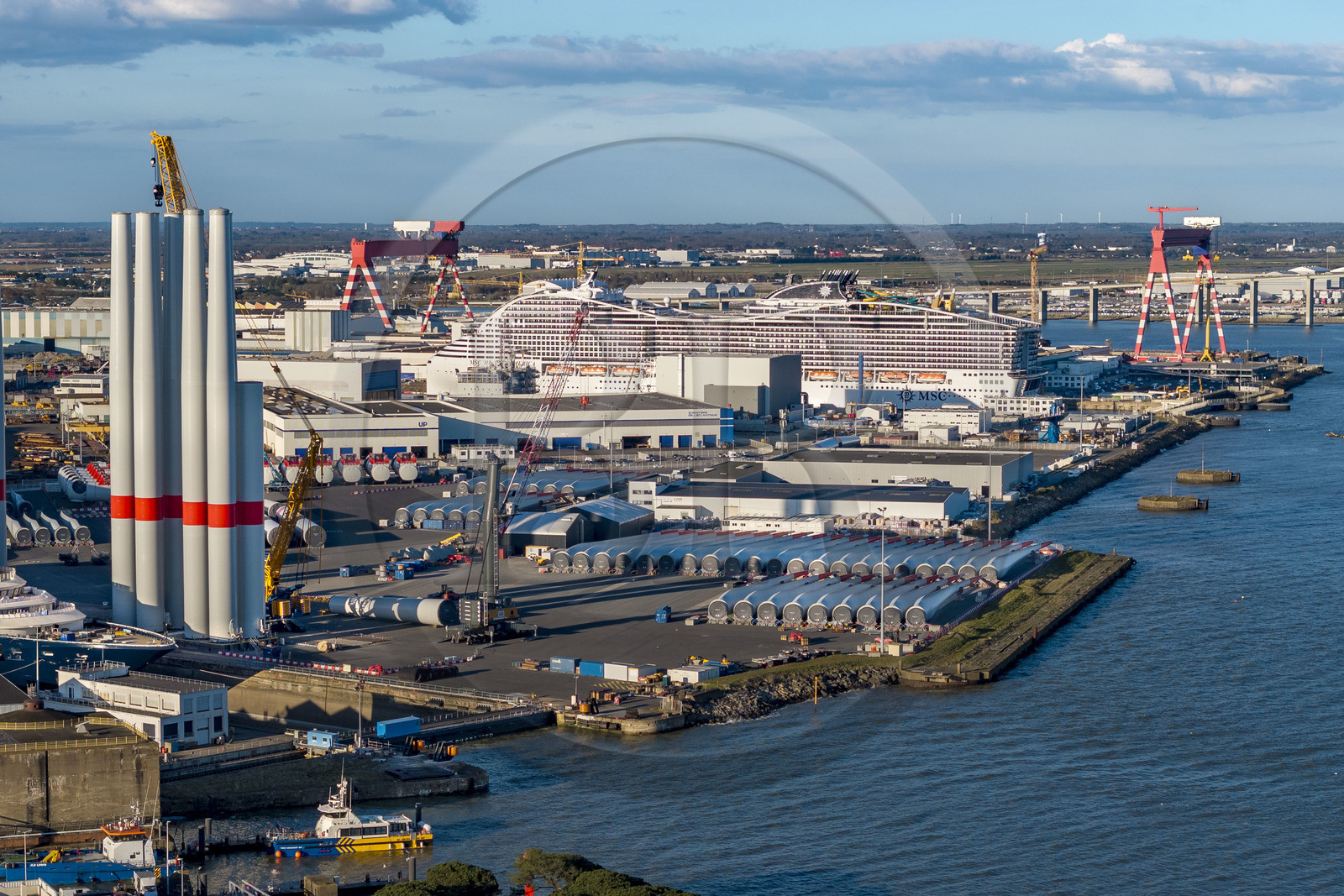 France, Loire-Atlantique (44), Saint-Nazaire, les tours d'éoliennes et les pales sont stockées avant embarquement, le paquebot de 333m MSC World America construit par les Chantiers de l'Atlantique en arrière plan (vue aérienne) France, Loire-Atlantique (44), Saint-Nazaire, les tours d'éoliennes et les pales sont stockées avant embarquement, le paquebot de 333m MSC World America construit par les Chantiers de l'Atlantique en arrière plan (vue aérienne)