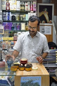 Sultanate of Oman, Muscat, old Muscat, the souk of Muttrah, vendor Fathima Bint Abdan Bin Hassan burning pure incense, portrait of Sultan Qaboos who died in 2020 in the background