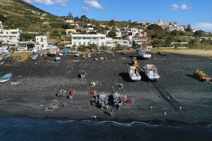 Italie, Sicile, iles Eoliennes, classées Patrimoine Mondial de l'UNESCO, ile de Stromboli, pecheurs sur la plage de Scari et le village de Stromboli en arrière plan (vue aérienne)