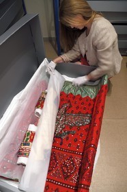 France, Alpes-de-Haute-Provence (04), vallée de l'Ubaye, Barcelonnette, villa mexicaine connue sous le nom de Villa Sapinière, Musée de la vallée, la conservatrice Hélène Homps dans la réserve du musée observe une robe brodée China poblana, costume national mexicain porté par les épouses des barcelonnettes pour le 14 juillet au Mexique