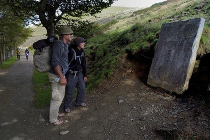 France, Pyrenees Atlantiques, Basque Country, Camino de Santiago (the Way of St. James) on the GR 65 between Saint Jean Pied de Port and Roncesvalles towards the Bentarte Pass, pilgrims in front of the stele indicating that Compostela is still 765 km