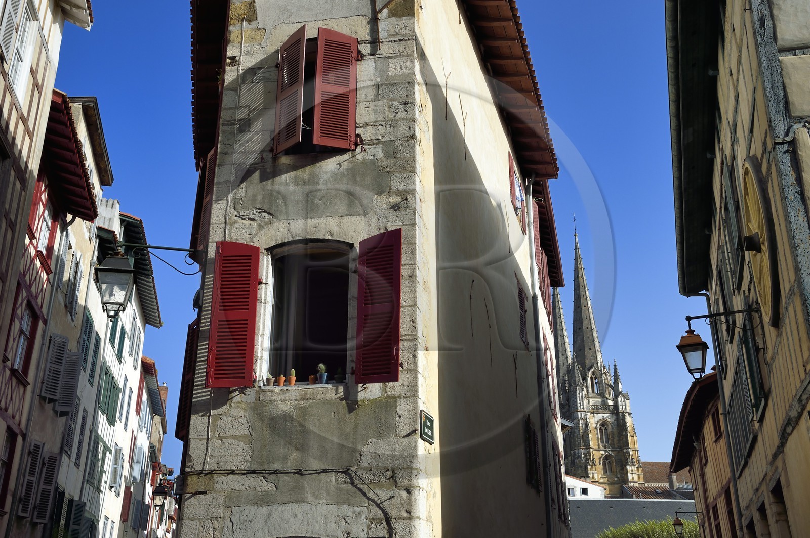 France, Pyrenees Atlantiques, Basque Country, Bayonne, corner house of the streets des Faures, Douer and Vieille Boucherie with the spires of St. Catherine's Cathedral in the background
