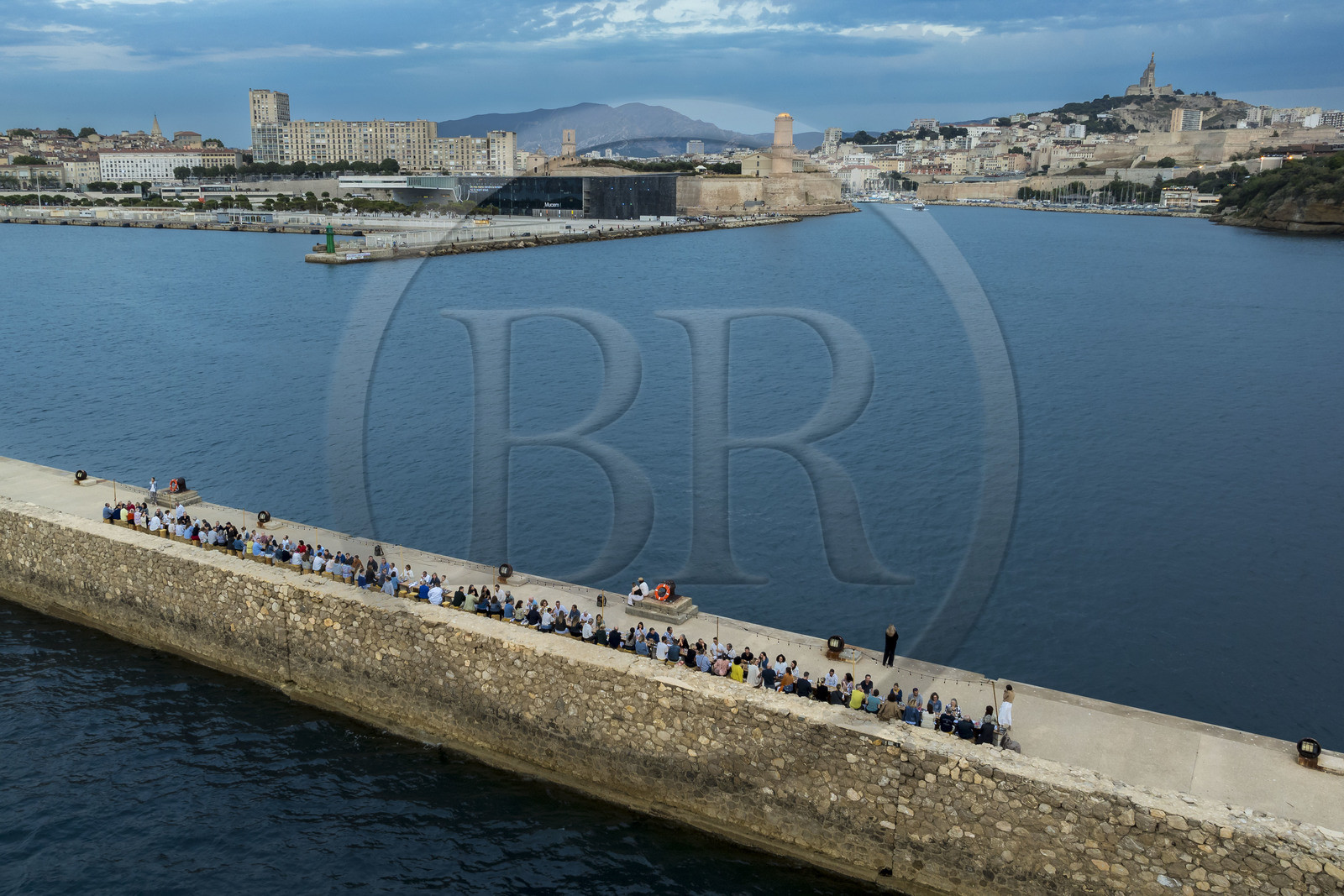 France, Bouches-du-Rhône (13), Marseille, Zone Euroméditerranée, grand port maritime de Marseille (GPMM), la digue du large, convives attablés à une grand table de banquet dressée par le chef Emmanuel Perrodin dans le cadre des Diners Insolites, le Mucem, le Fort Saint-Jean et la basilique Notre Dame de la Garde en arrière plan (vue aérienne)