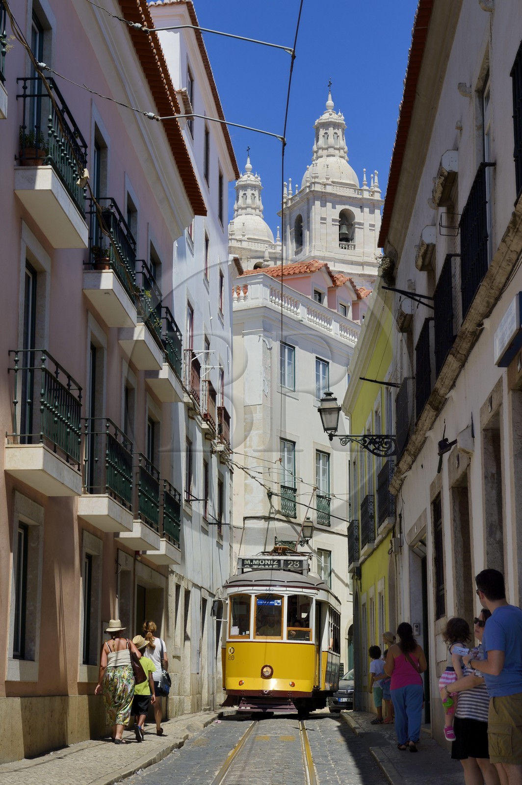 Portugal, Lisbon, Alfama district, tram (electricos) along Rua das Escolas Gerais with the tower of Sao Vicente de Fora church