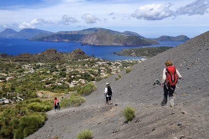 Italy, Sicily, Aeolian Islands, listed as World Heritage by UNESCO, Vulcano Island, hikers on the flanks of the crater of volcano della Fossa, Lipari Island in the background