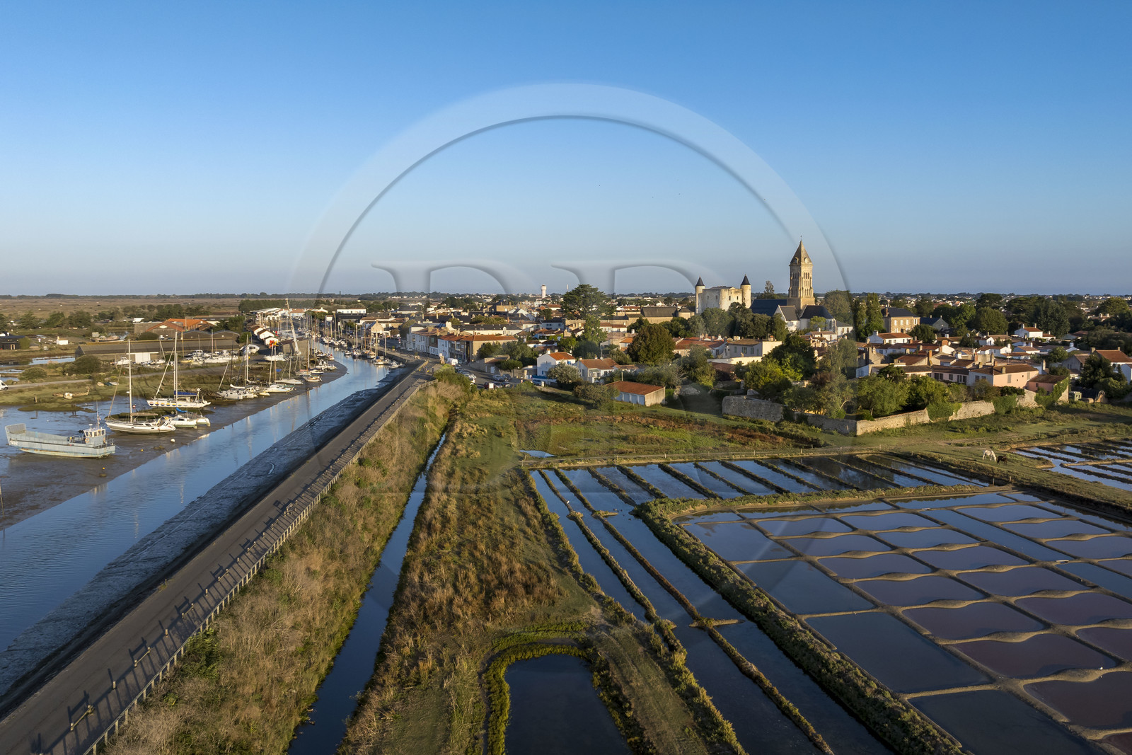France, Vendee, Noirmoutier island, Noirmoutier en l’Ile, the marshes of Müllembourg along the  port access channel Jacobsen road, the medieval castle and the Saint-Philbert church in the background (aerial view)