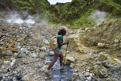 Caribbean, Dominica Island, Castle Bruce, Morne Trois Pitons National Park listed as World heritage by UNESCO, Valley of Desolation, hiker crossing a river of hot springs, whose unique color is due to the presence of calcium, carbon, sulfur and iron, on the trail leading to Boiling Lake