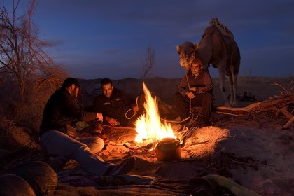 Iran, Isfahan province, Dasht-e Kavir desert, Mesr in Khur and Biabanak County, .camel driver and his dromedary at a campfire in Kuh-e Sefid bivouac